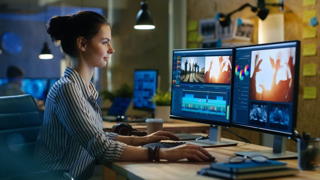 A woman working on two computer screens, creating storyboard for video marketing content