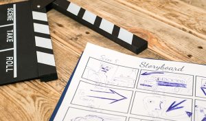Clapperboard And Paper With Drawings, Representing A Storyboard For Video Marketing Content