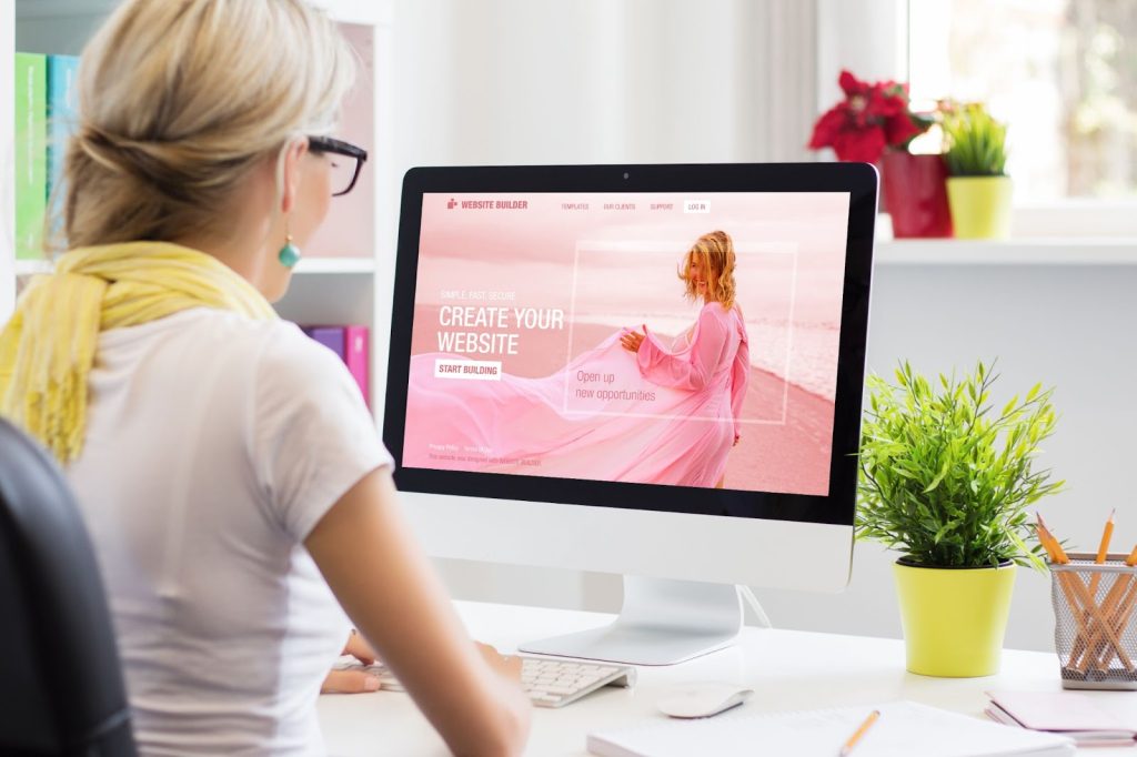 A woman sits at a desk, focused on her computer screen, working on her WordPress website development.