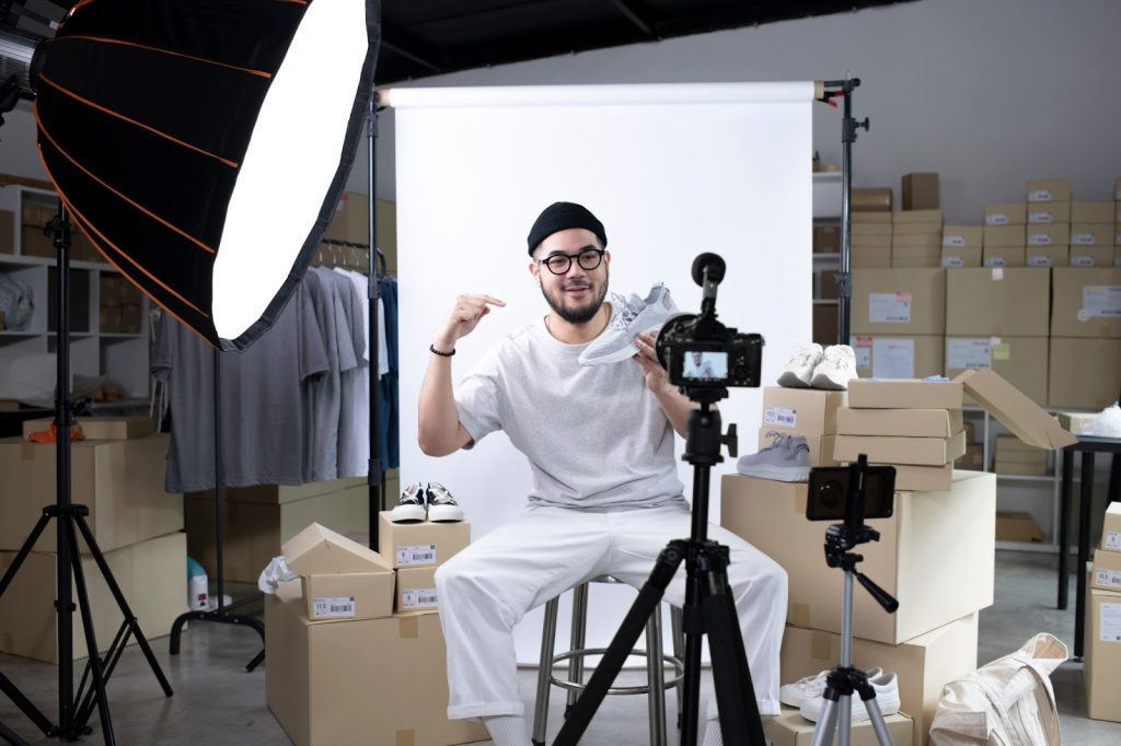 A man seated on a chair, equipped with a camera and tripod, engaged in influencer marketing for digital campaigns.