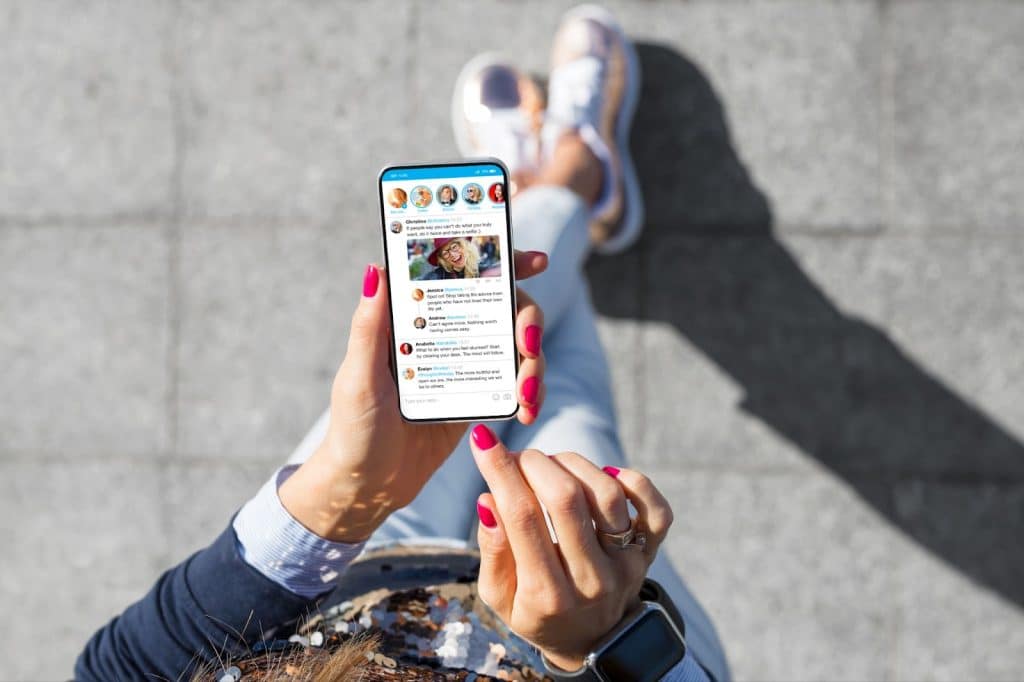 A woman using a smartphone to manage and schedule social media posts for digital marketing purposes.