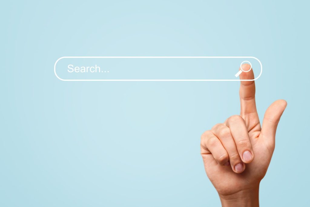 Hand pointing to a search button on a blue background, symbolizing SEO tools and content creation strategies.