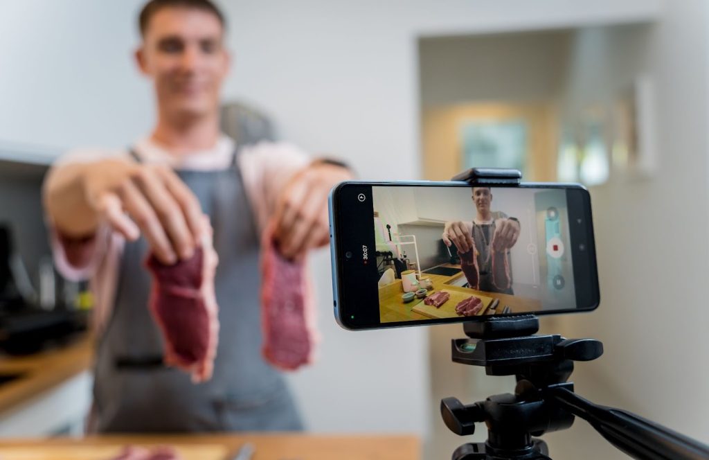 A man filming meat with a camera, showcasing the expertise of a Utah digital marketing agency in creating marketing videos.