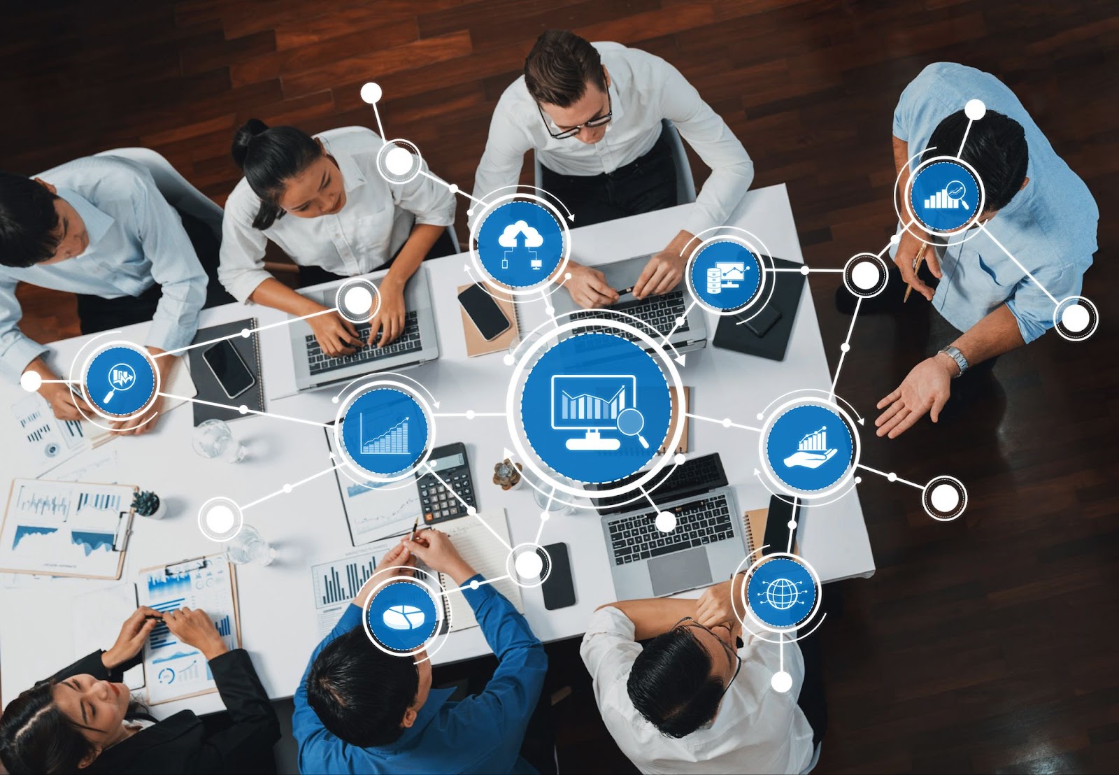 A team working at a table with laptops, surrounded by digital icons representing data analysis and connectivity.