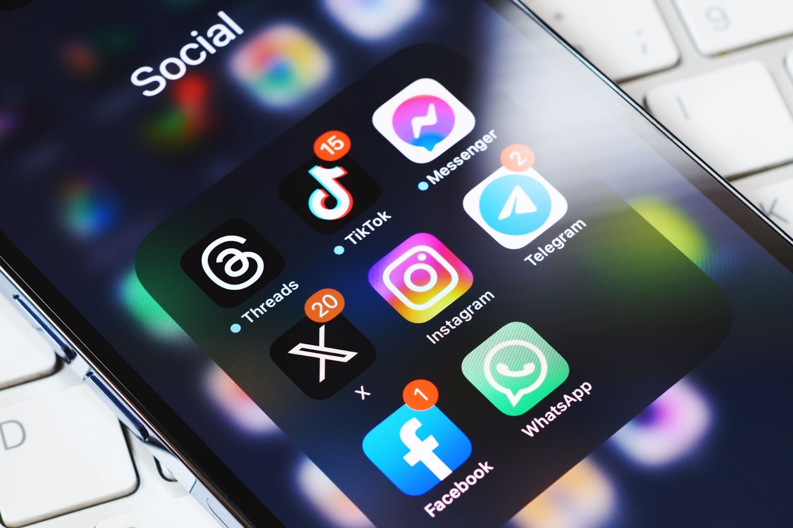 Smartphone screen displaying various social media app icons on a keyboard.