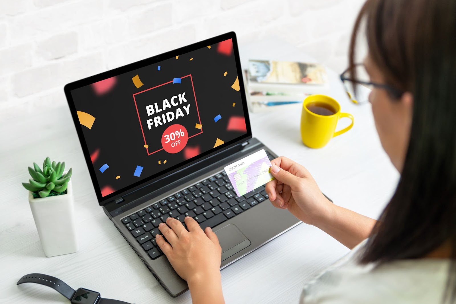 Person shopping online with a credit card on a laptop displaying a Black Friday 30% off deal.