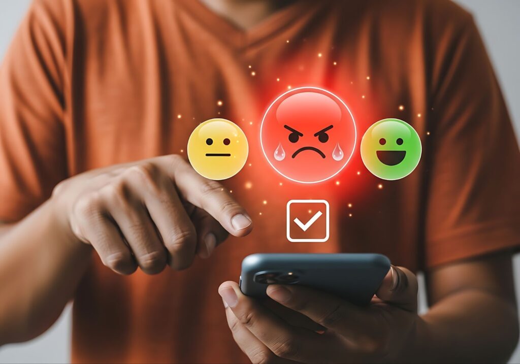 Person selecting an angry emoji on a smartphone with other emojis displayed.