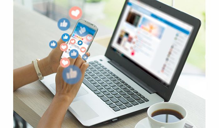 A woman using a laptop with social icons on the screen, representing the concept of social media marketing