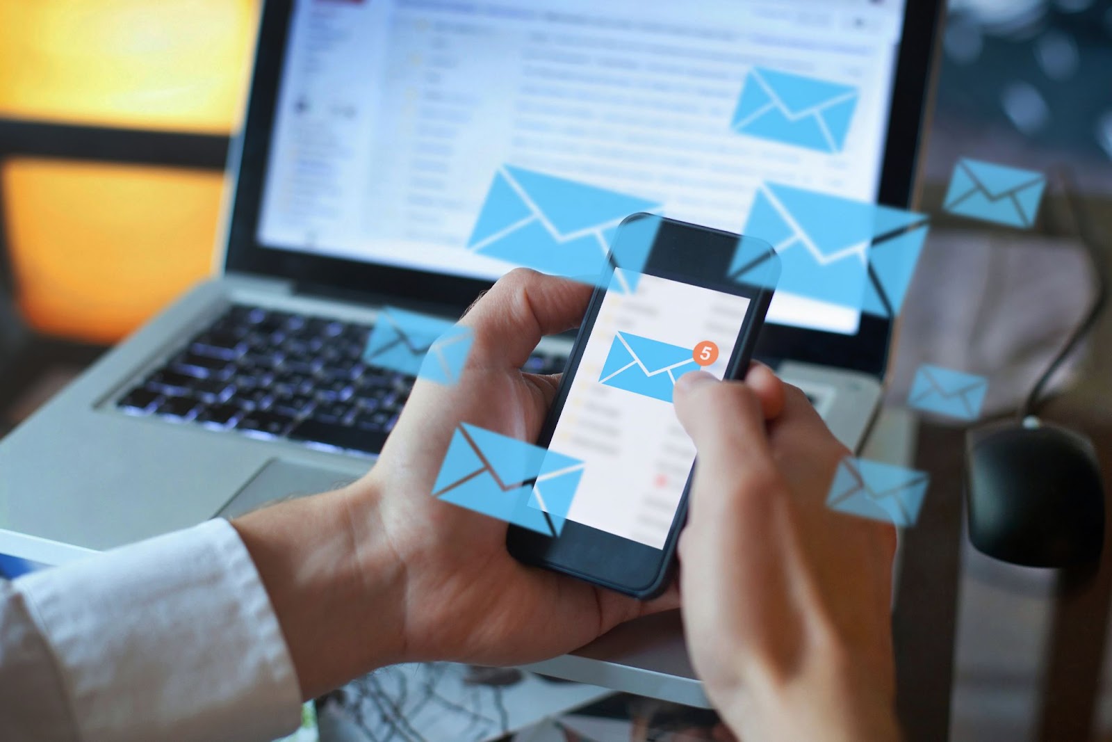 Close-up of hands typing on a laptop with digital email icons floating above the keyboard.
