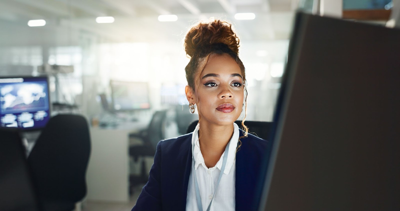 A business-suited woman focuses on a computer screen, likely reviewing search results from ChatGPT.
